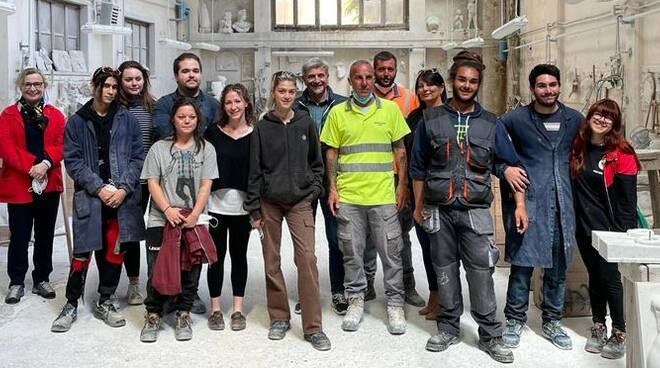 Fotografia di gruppo degli studenti, dirigente scolastico e rappresentanti della Cooperativa Cavatori di Lorano all'interno del Laboratorio del marmo dell'Istituto Tacca